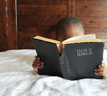 Kind liest in der Bibel
